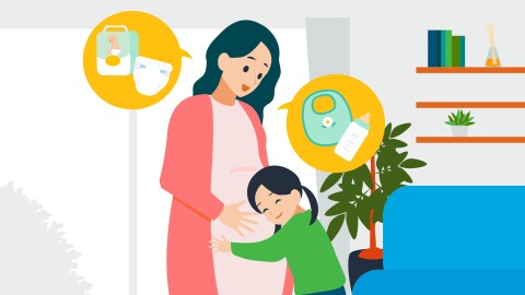 妊娠している母親のおなかに抱きついている少女。母親はオムツや哺乳瓶について少女に話している