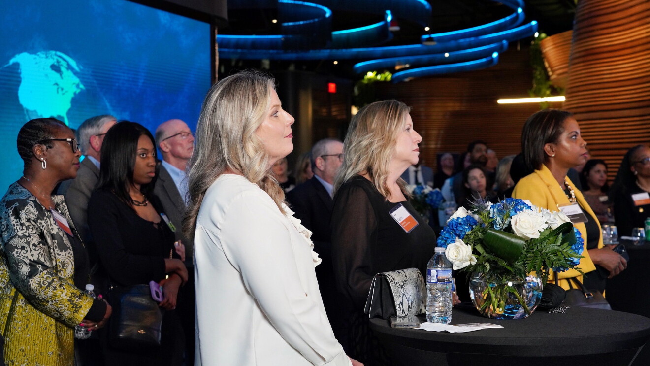Professional gathering with women in foreground, floral centerpiece visible