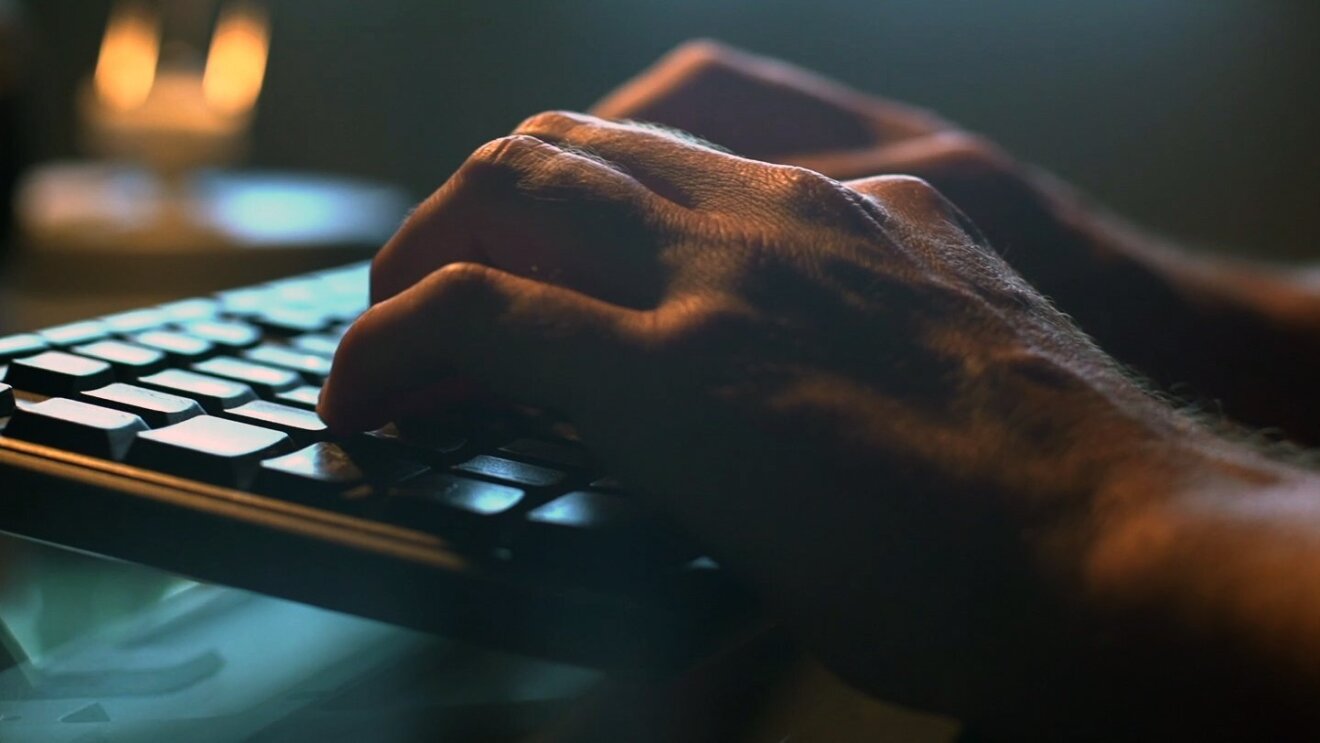 Primer plano de dos manos y un teclado.