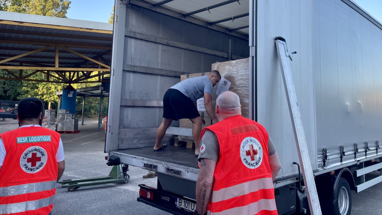 Red Cross volunteers supervising the unloading of palletized relief supplies from Amazon from a delivery truck
