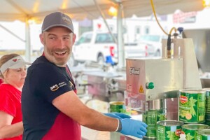 Matt Idalia wears a red apron and opens up cans of green beans as he volunteers for AWS Disaster Response.