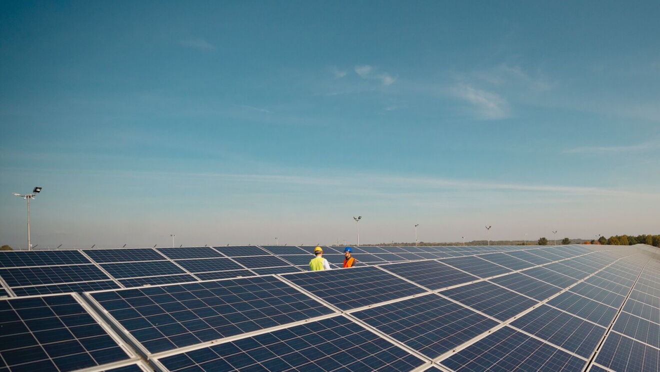 carbon-free energy , a solar panel field with workers inspecting under blue sky