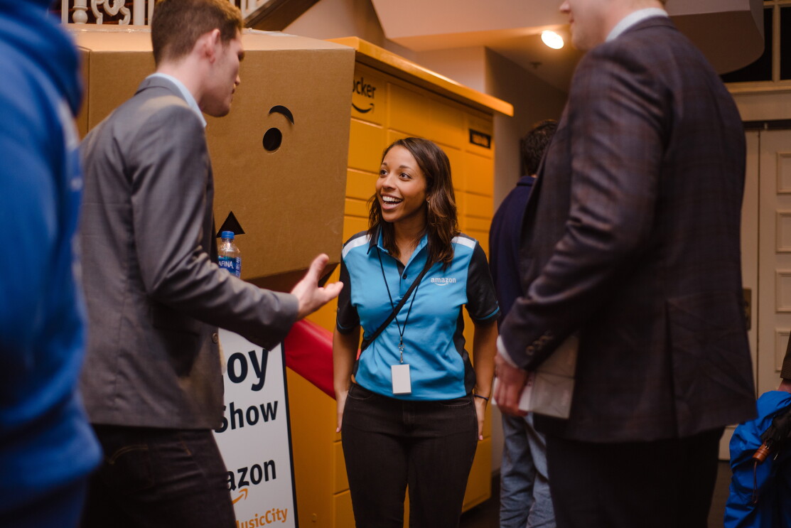 A woman wearing an Amazon-branded shirt speaks with two men at an event in Nashville.