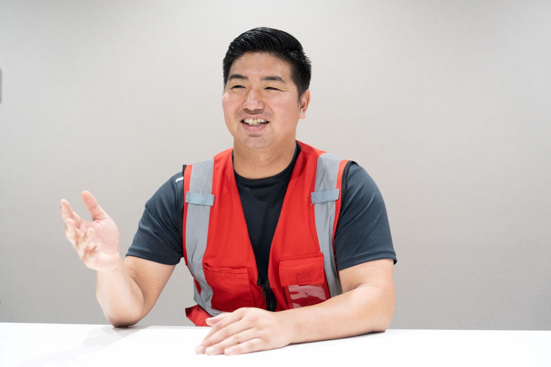 赤いベストを着ている男性が手振りをしながら話している