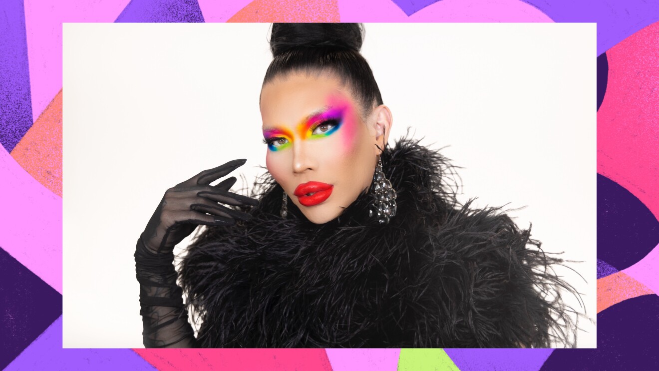 基莫拉站在白色背景前的大头照。她画着迷人的彩虹妆,涂着鲜红色的口红。