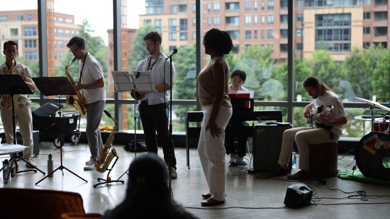 Jazz ensemble practicing near large windows overlooking apartments