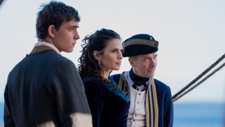 Tom Sweet as Jim Hawkins, Hayley Atwell as Bess Hawkins, and Tristan Sturrock as Captain Smollett stare off camera.