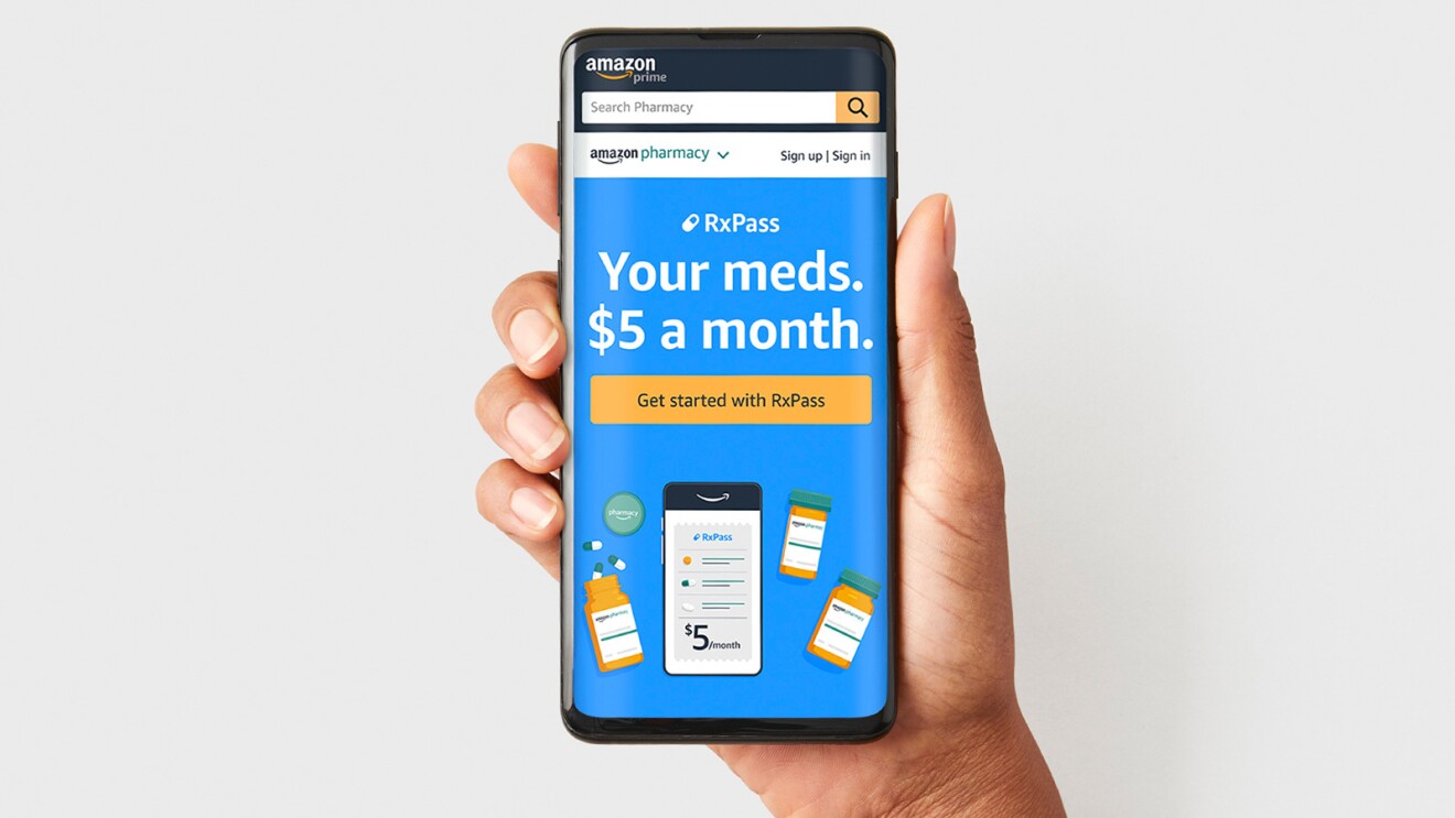 A hand olds up a mobile phone with the Amazon Pharmacy prescription subscirption page pulled up on the Amazon app.