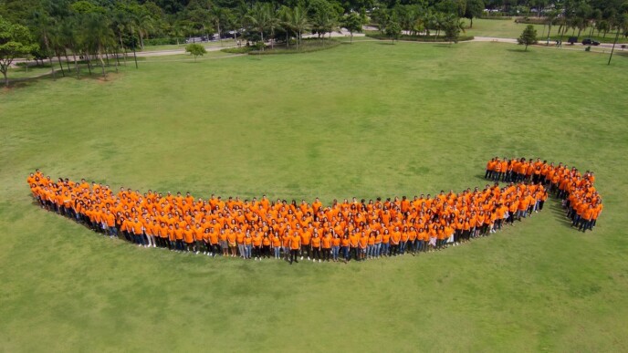 Equipe que fez o lançamento da expansão do varejo forma o logo da Amazon, no Brasil