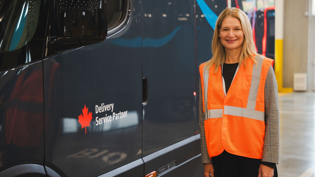 Un employé d'Amazon se tient près d'une camionnette de livraison Amazon