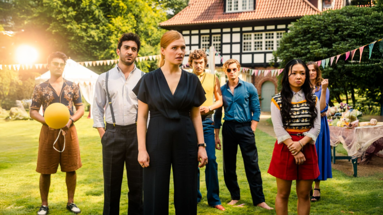 Sonja Wiesser as Lydia Beaufort, Andrea Guo as Lin Wang, Justus Riesner, and others, starting intently in one direction at a Garden party from a scene in Maxton Hall Season 3
