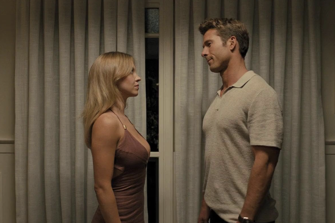 A man and woman standing in front of each other in a room, looking at each other.