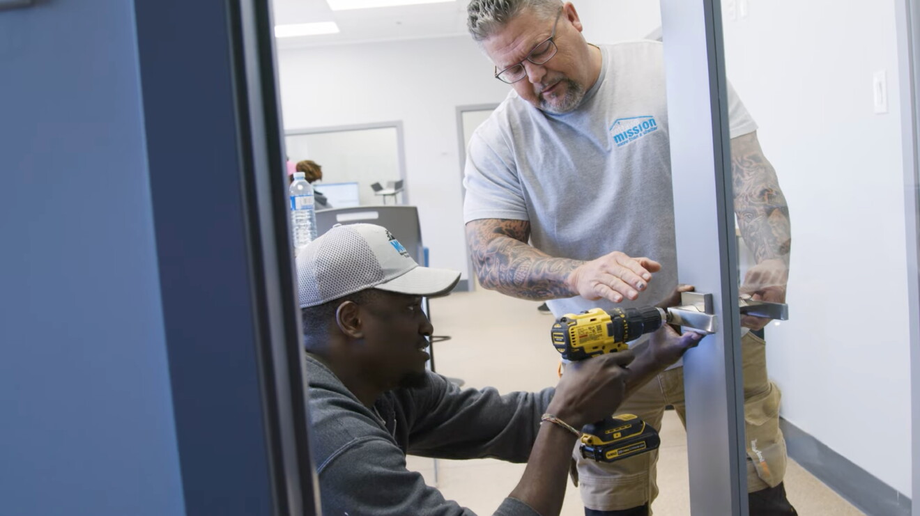 two men drilling nails into wall