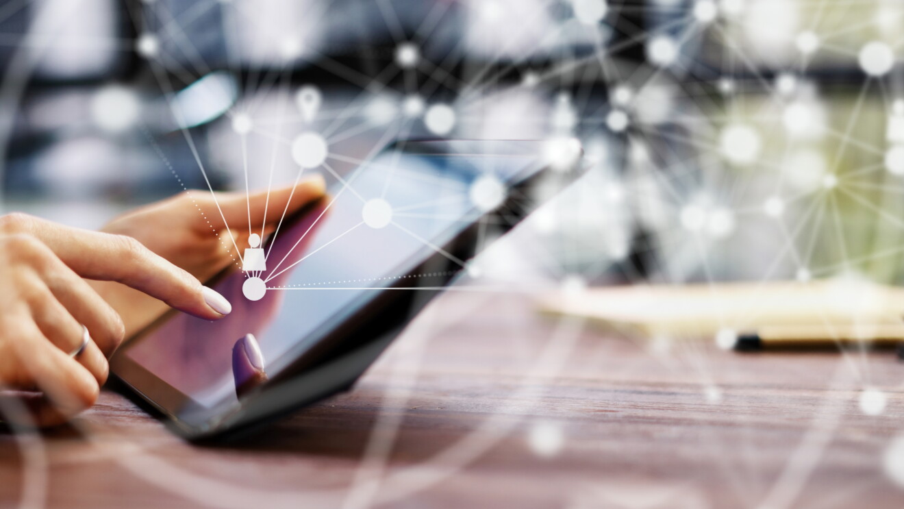 Hands touching a tablet with images showing how it's connected on a network.