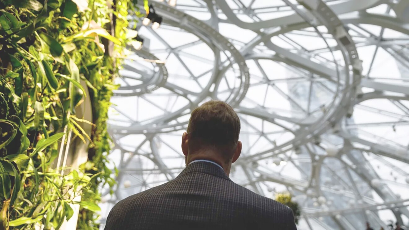 An image of the back of a man in a suit walking inside The Seattle Spheres at Amazon’s headquarters.