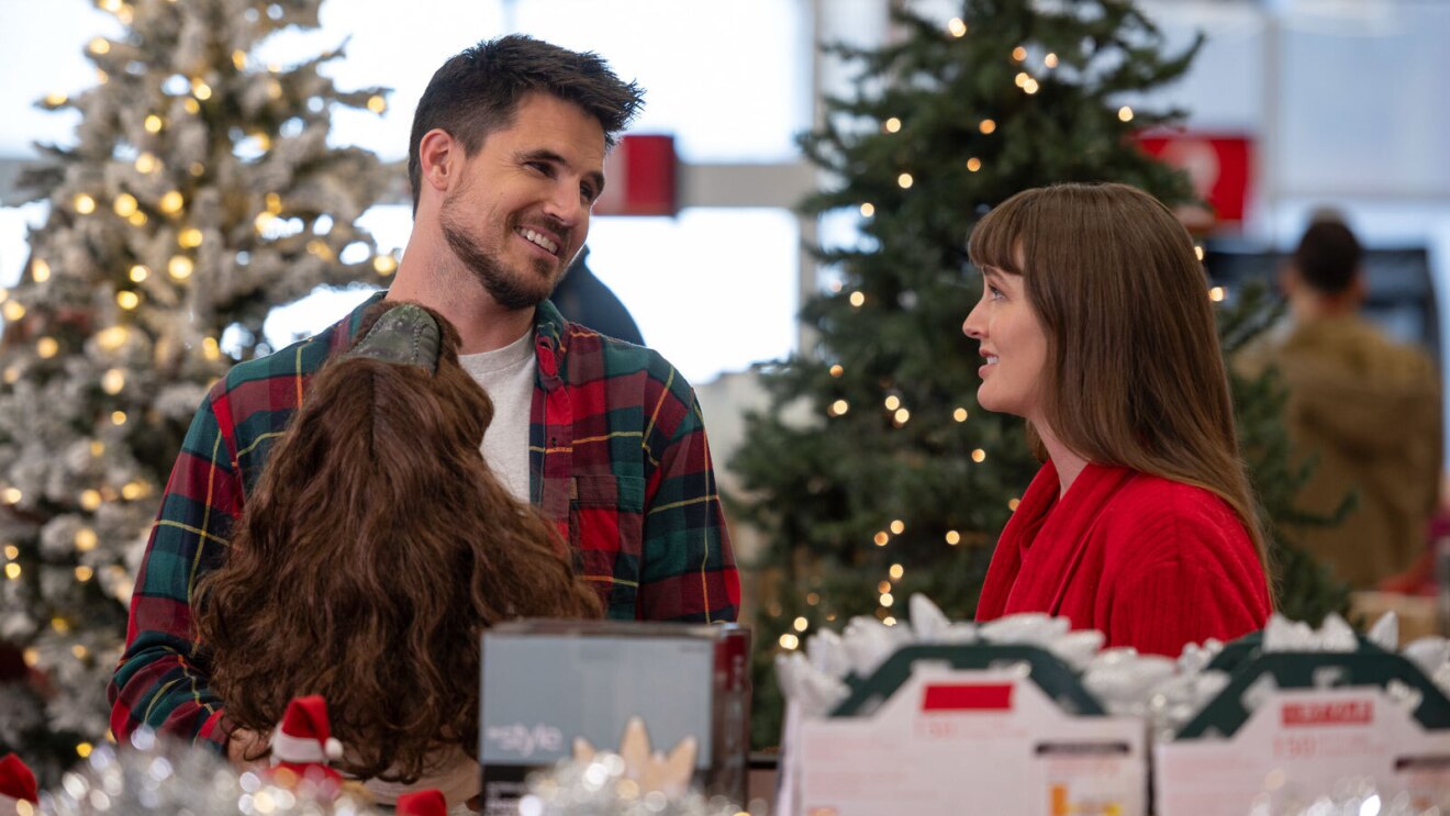 An image of a man and a woman standing in the middle of a christmas display, looking at each other and smiling