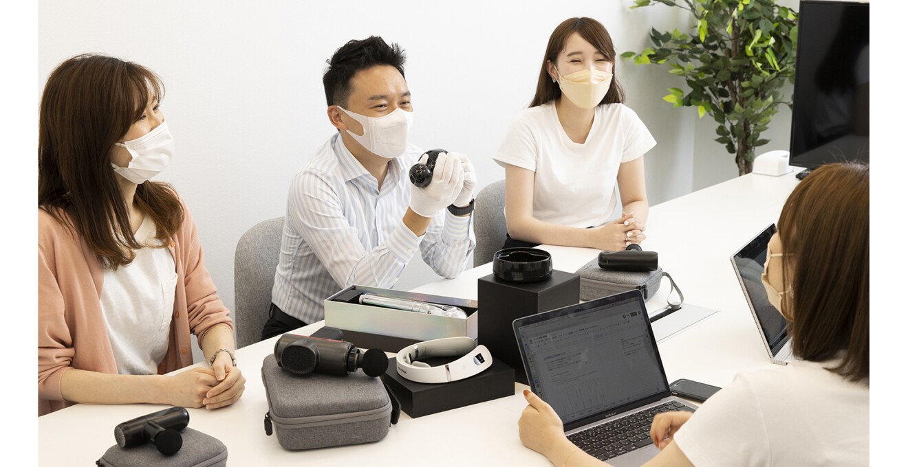 商品を手に女性スタッフ達と話し合う薛さん