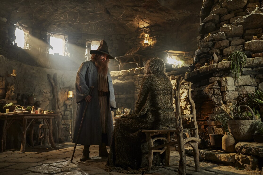 Rory Kinnear (Tom Bombadil) and Daniel Weyman (The Stranger) having a discussion in an old stone like hut in the Lord of the Rings: The Rings of Power