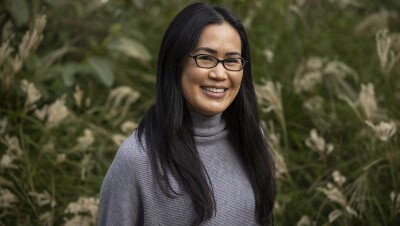 一个女人在外面的绿色区域前微笑着拍专业照片的形象。