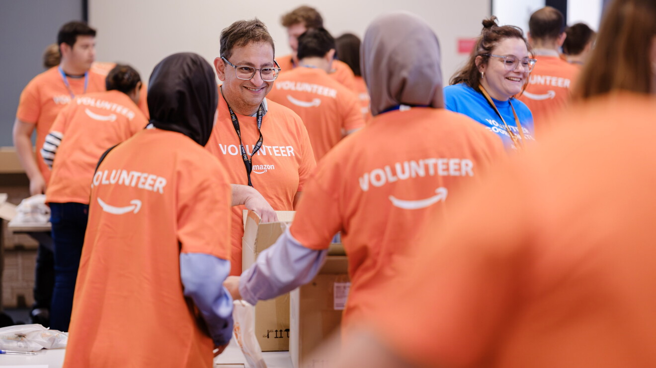 Amazon volunteers in orange shirts helping at community event 