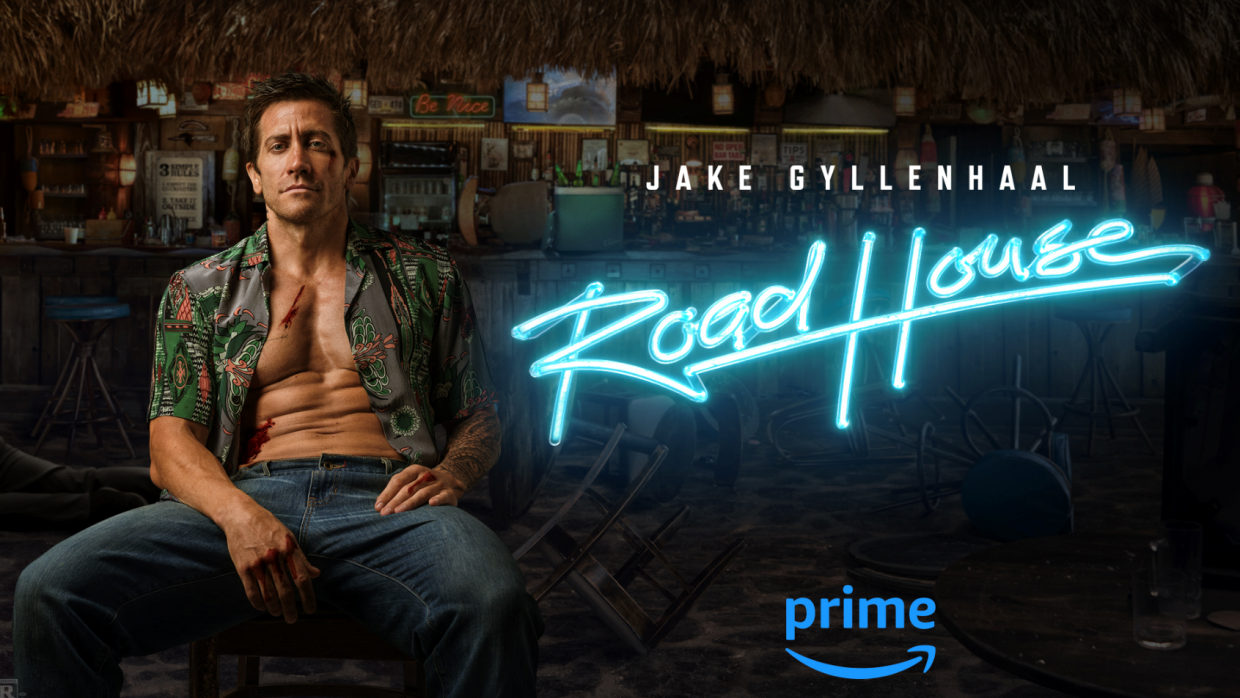 Dalton (Jake Gyllenhaal) is sitting on a bar with a floral-pattern shirt. It's a poster for new Amazon Original movie, Road House. 