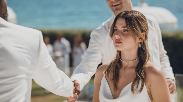 Culpa Nuestra: A woman in a white dress looks into the distance