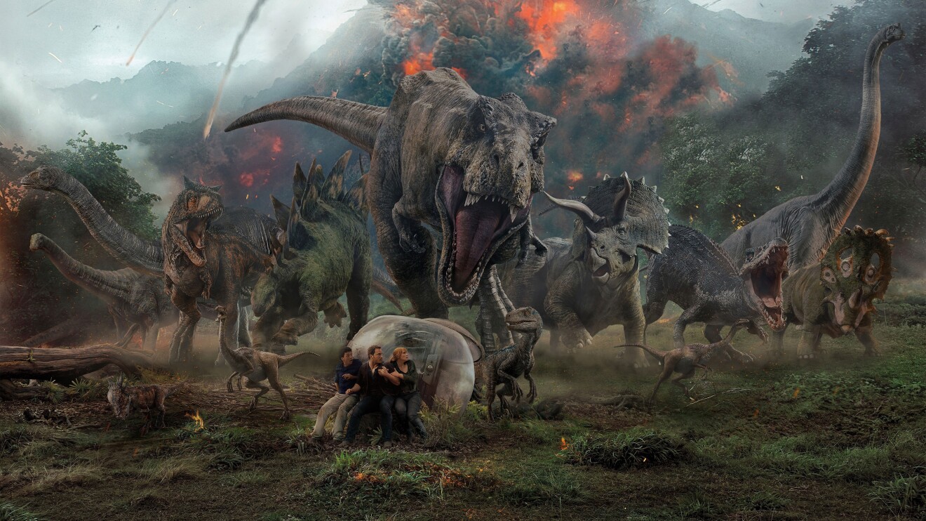 Dinosaurs rampage through prehistoric jungle amid volcanic eruption.