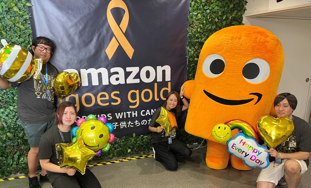 Amazon Goes Goldのパネルの前で記念撮影をするAmazonの社員たち