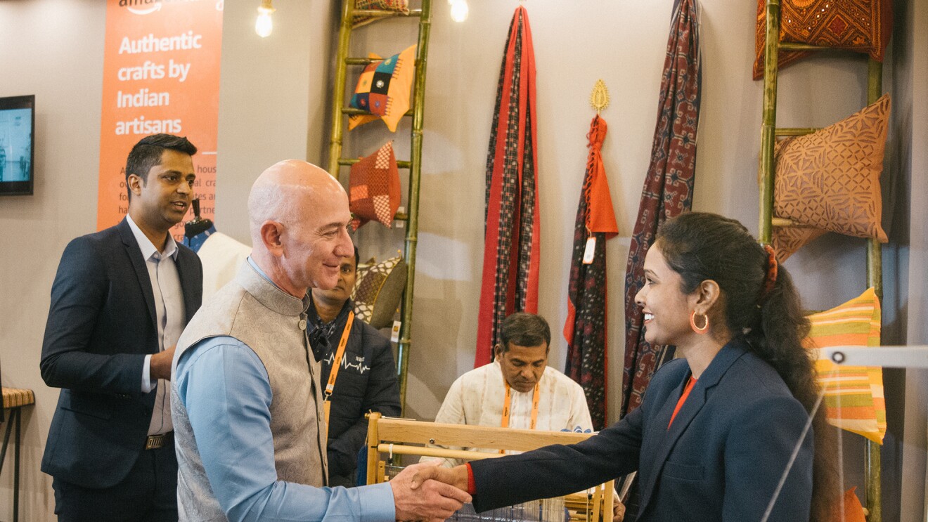 Jeff Bezos shakes the hand of a woman artisan and small business owner.