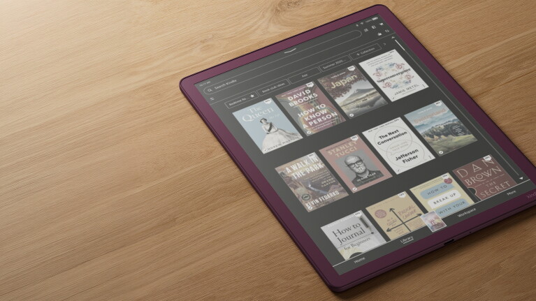 Amazon Kindle displaying a library of book covers on a wooden table