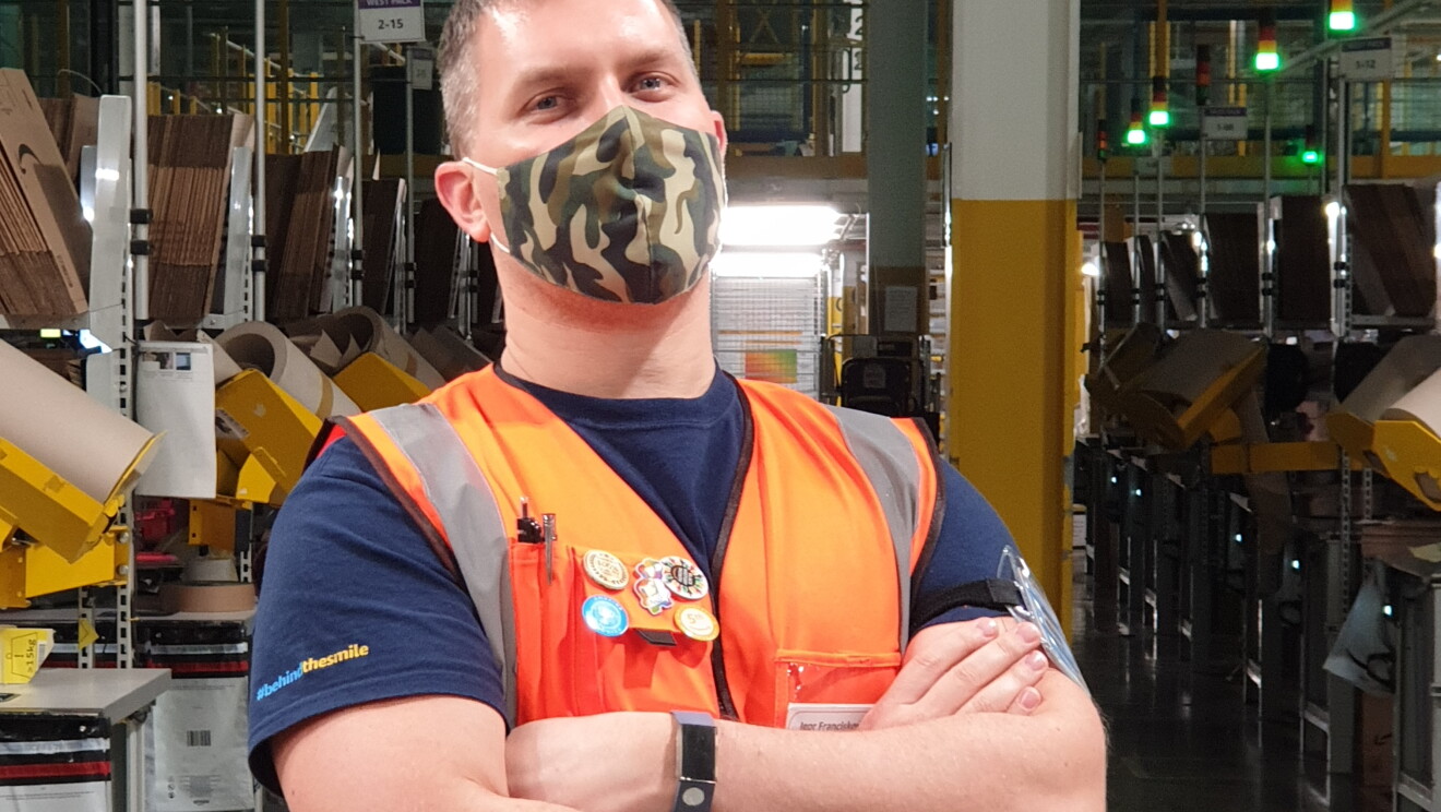 Igor Franciskovity, Area Manager at Amazon's fulfilment centre in Tilbury pictured cross-armed and wearing a high visibility vest and mask, with the shop-floor in the background.