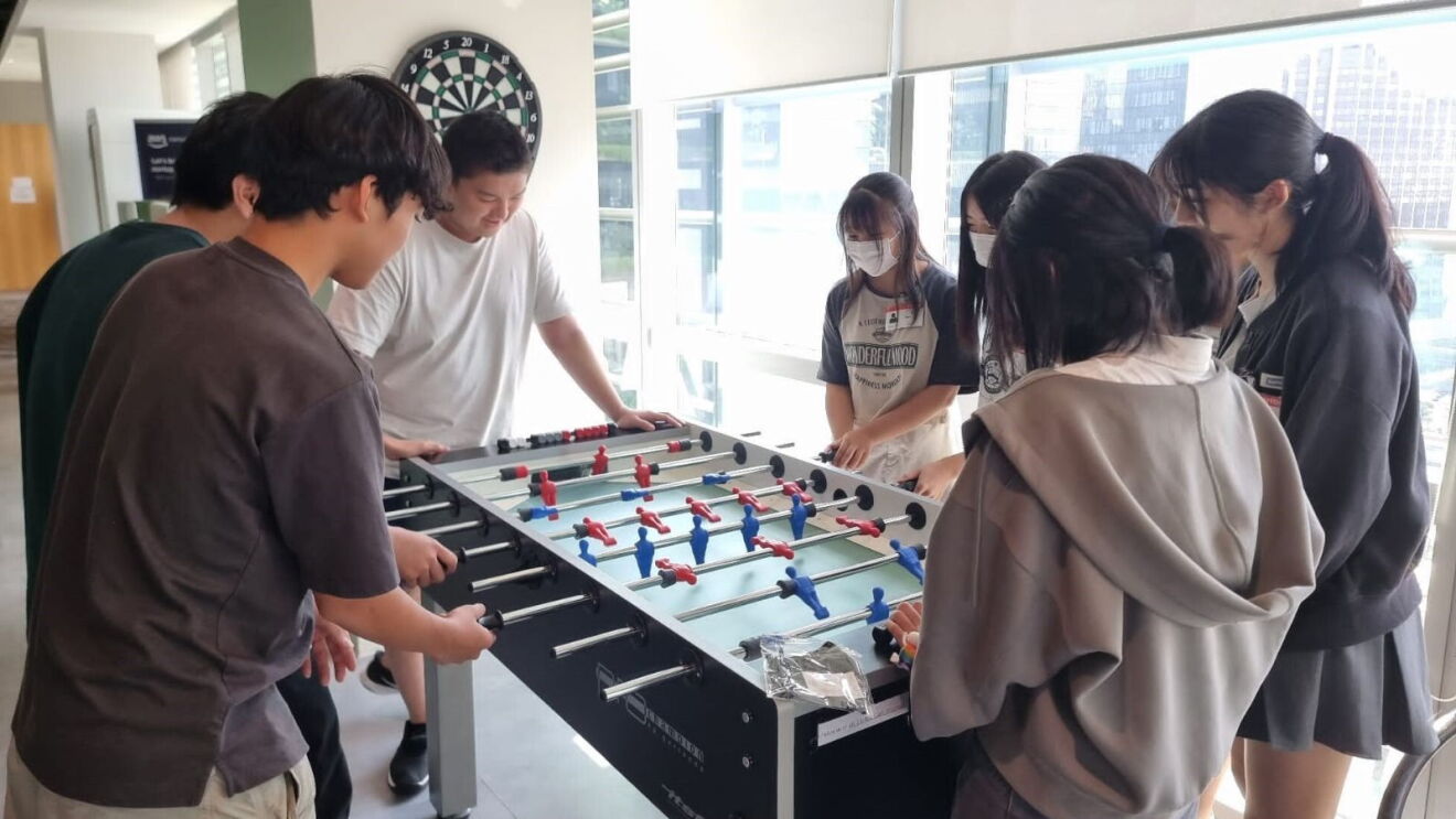 Japanese YouTuber Ghib Ojisan and Japanese high school students playing foosball in the AWS Singapore office.