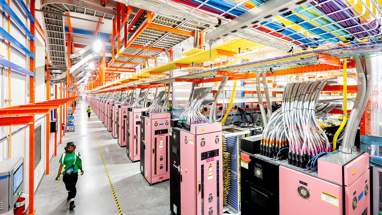 A data center technician walking within a data center hall near UltraServers.