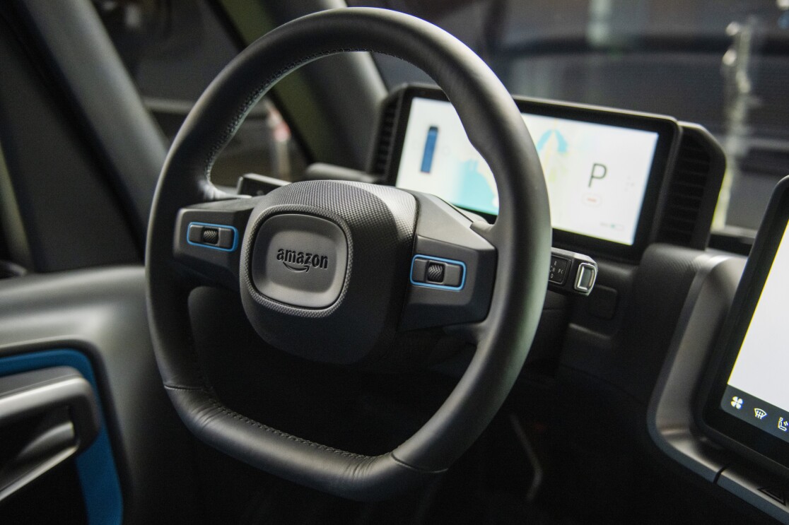 A steering wheel with the Amazon logo includes built-in microphones and speakers.