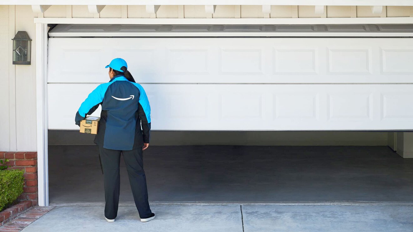 An Amazon employee delivering a package inside a garage. 