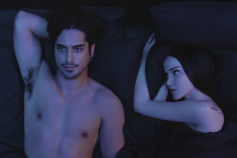 Two people lying in bed in dark lighting