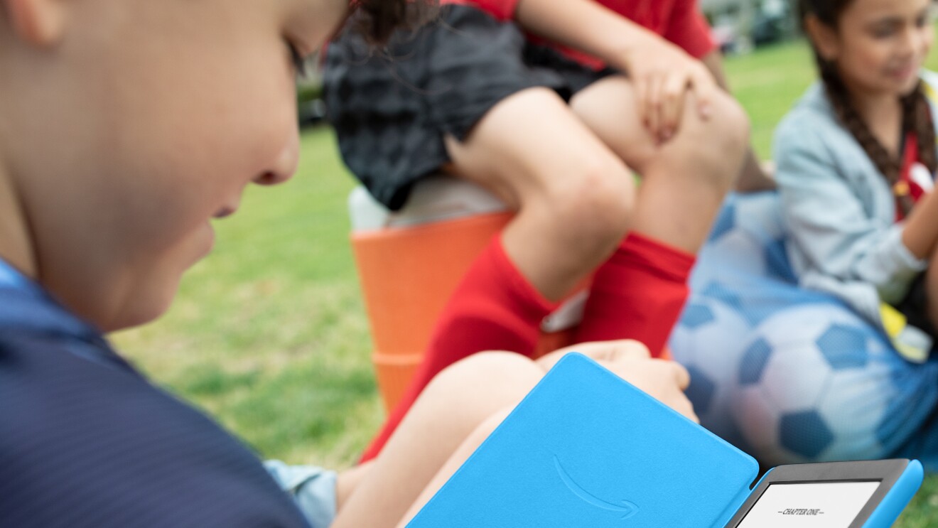 Child reading a book at the park on the Amazon Kindle Kids Edition