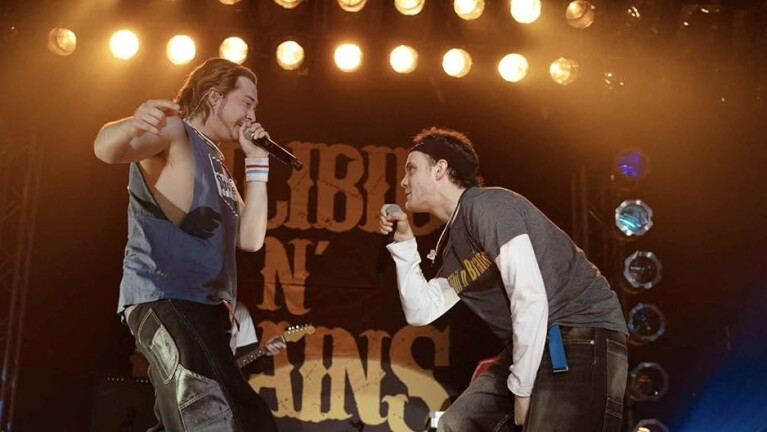 Two men with microphones perform on stage 
