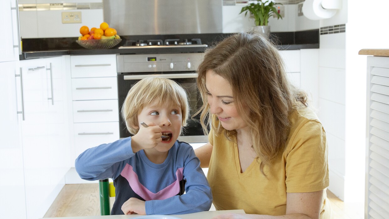 Sophia Proctor and her son sitting at the dinner table with a Munchy Play Bowl full of cereal.