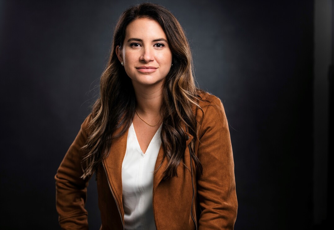 An image of Allie Miller, a White woman with long brown hair wearing a white T-Shirt and a tan jacket.