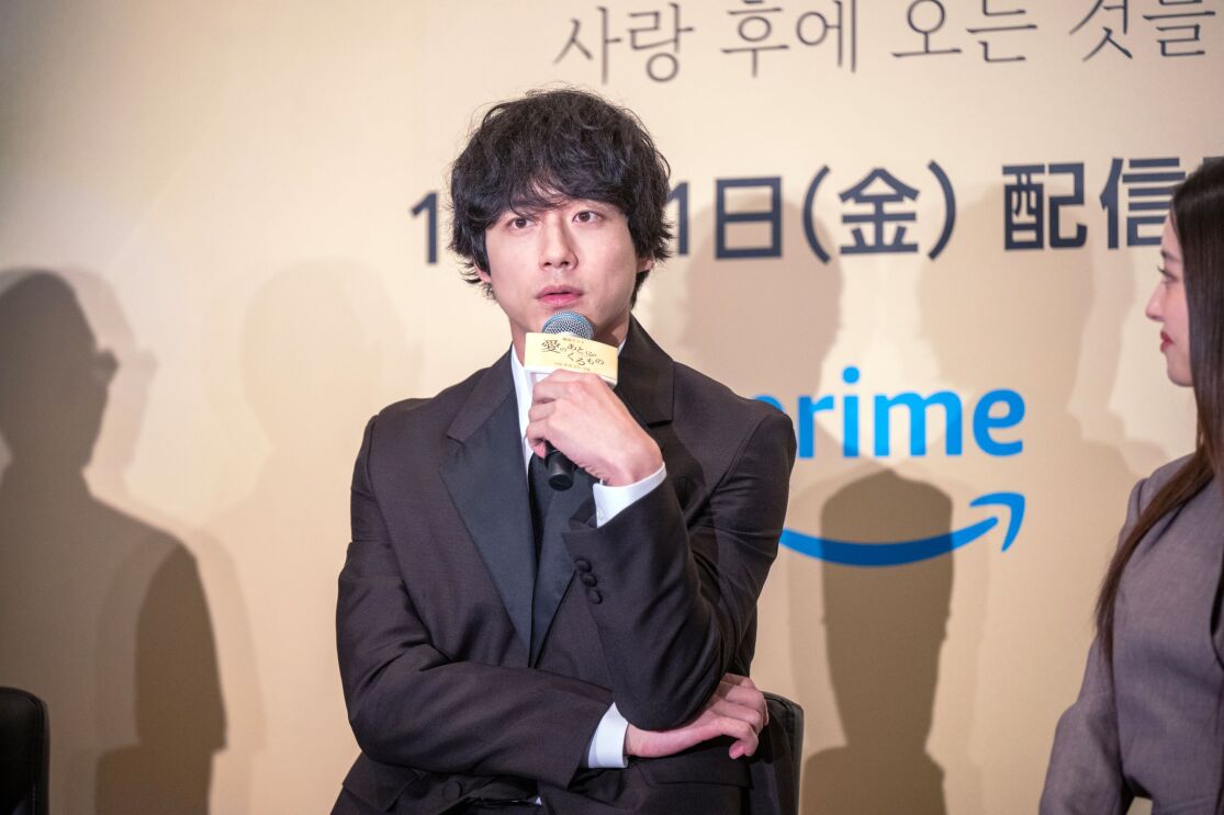 マイクを左手に持っている男性が前に向かって話している