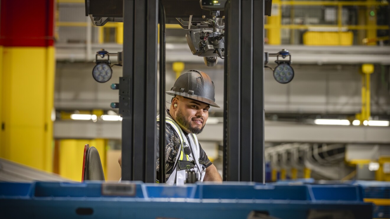 Amazon employee in hard hat operating forklift in facility