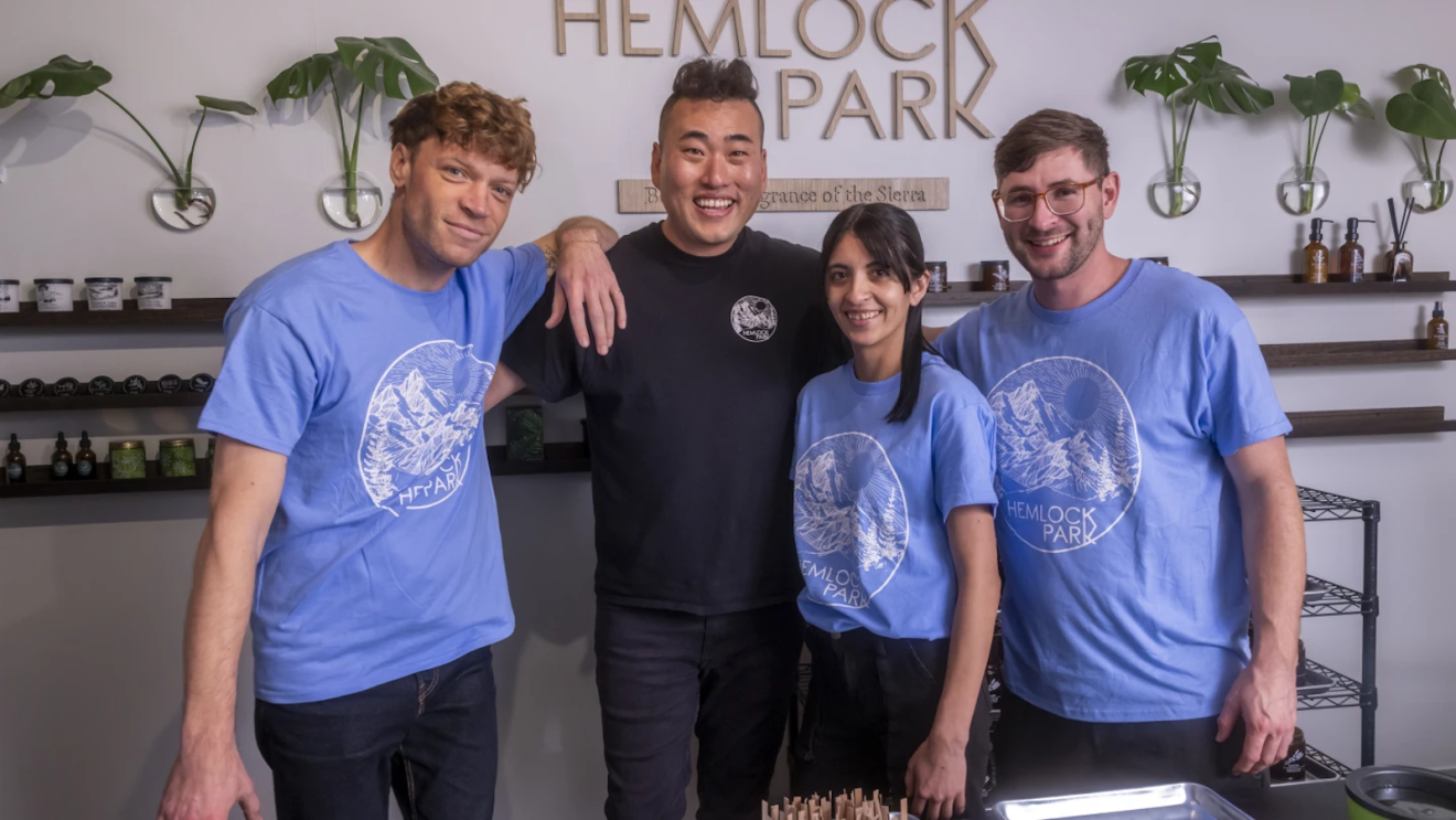 Hemlock Park founder Mikey Kim standing with three employees in their candle production studio