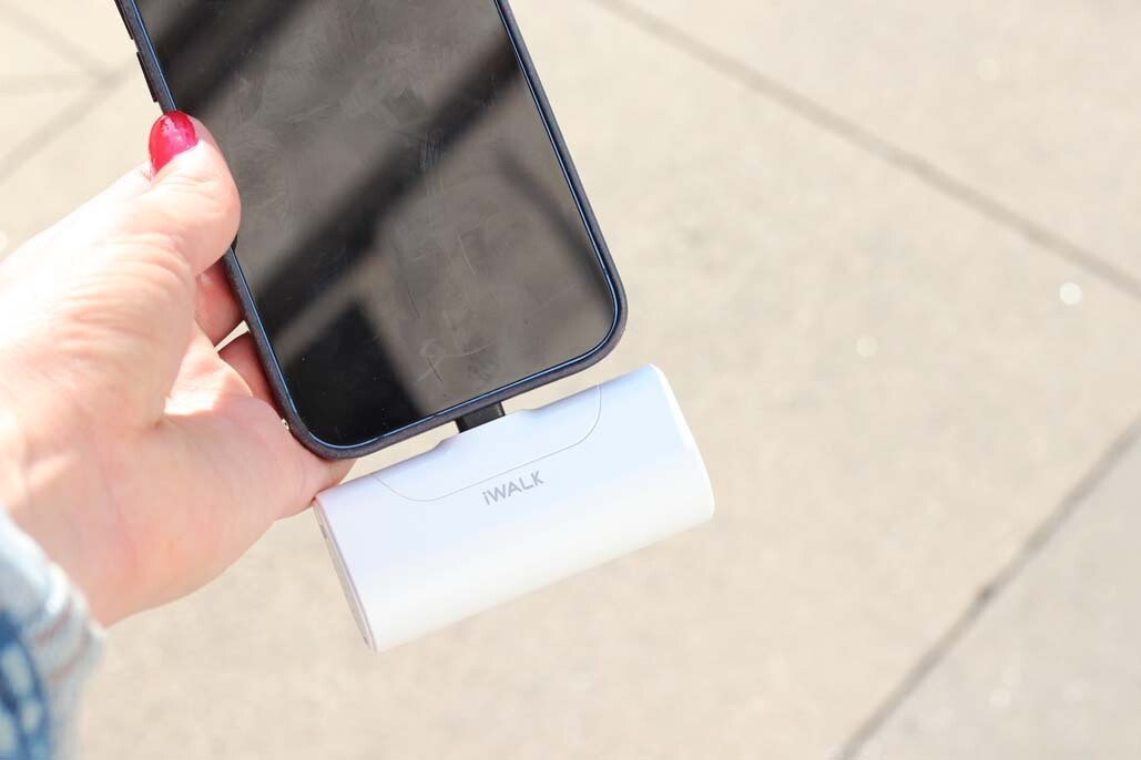 An image of a hand holding a phone with a portable charger attached.