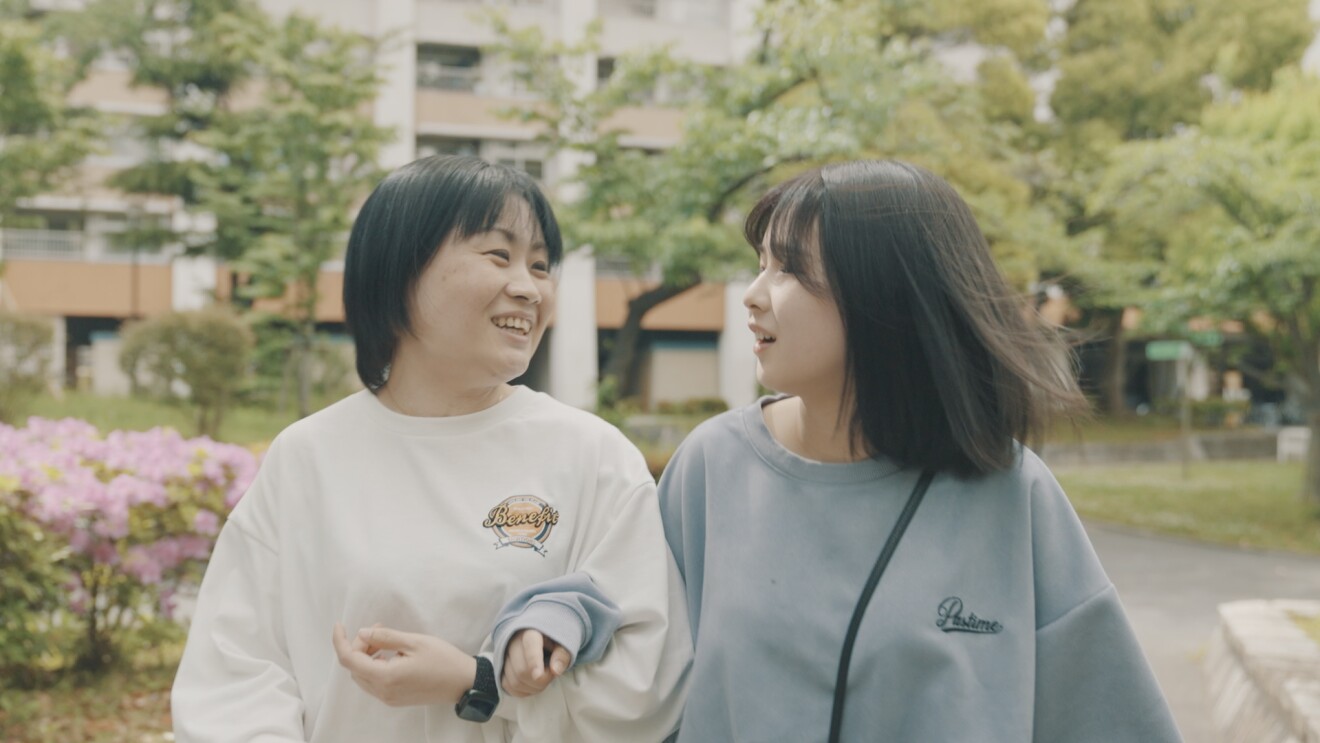 腕を組み嬉しそうに歩く青木さんと娘さんの写真
