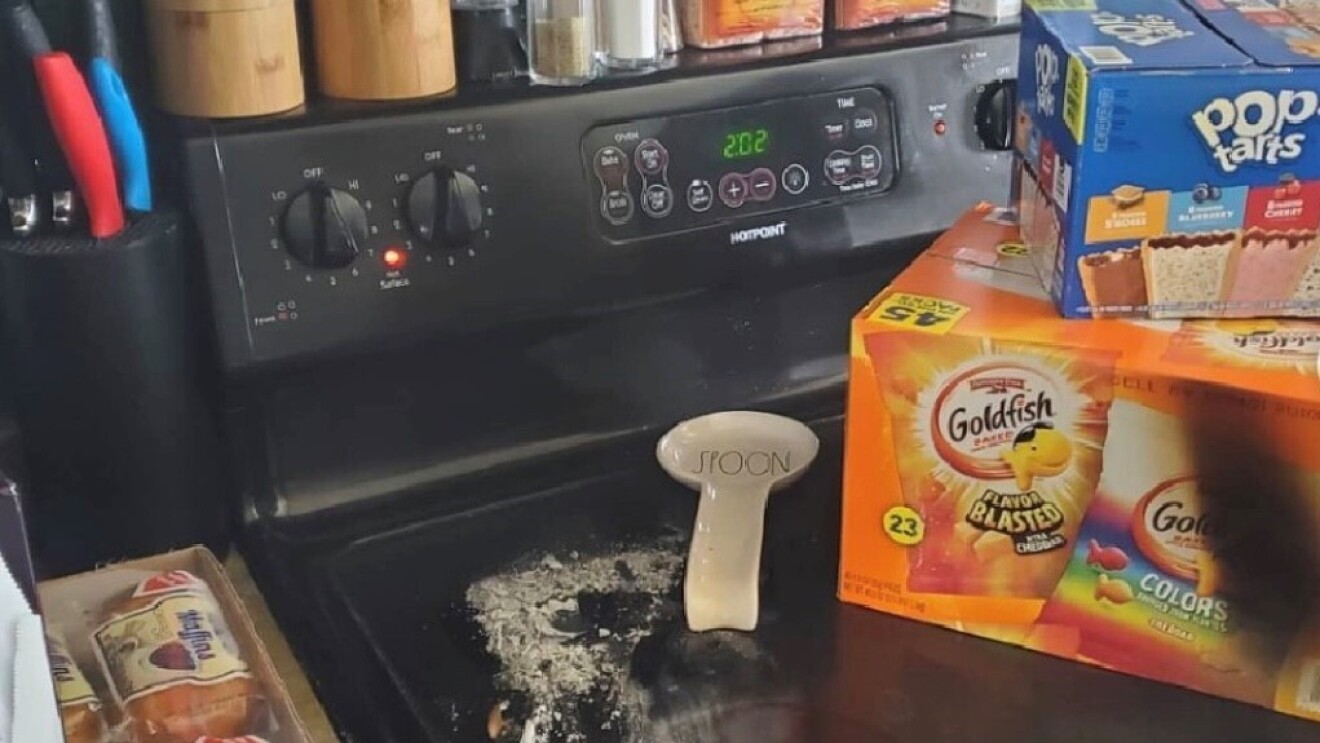 An image of a stove with spices stacked on top of it and food boxes on the burner.