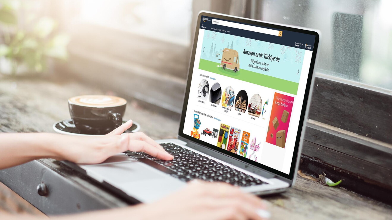 Woman types on a notebook computer, the screen shows Amazon's Turkey website. 