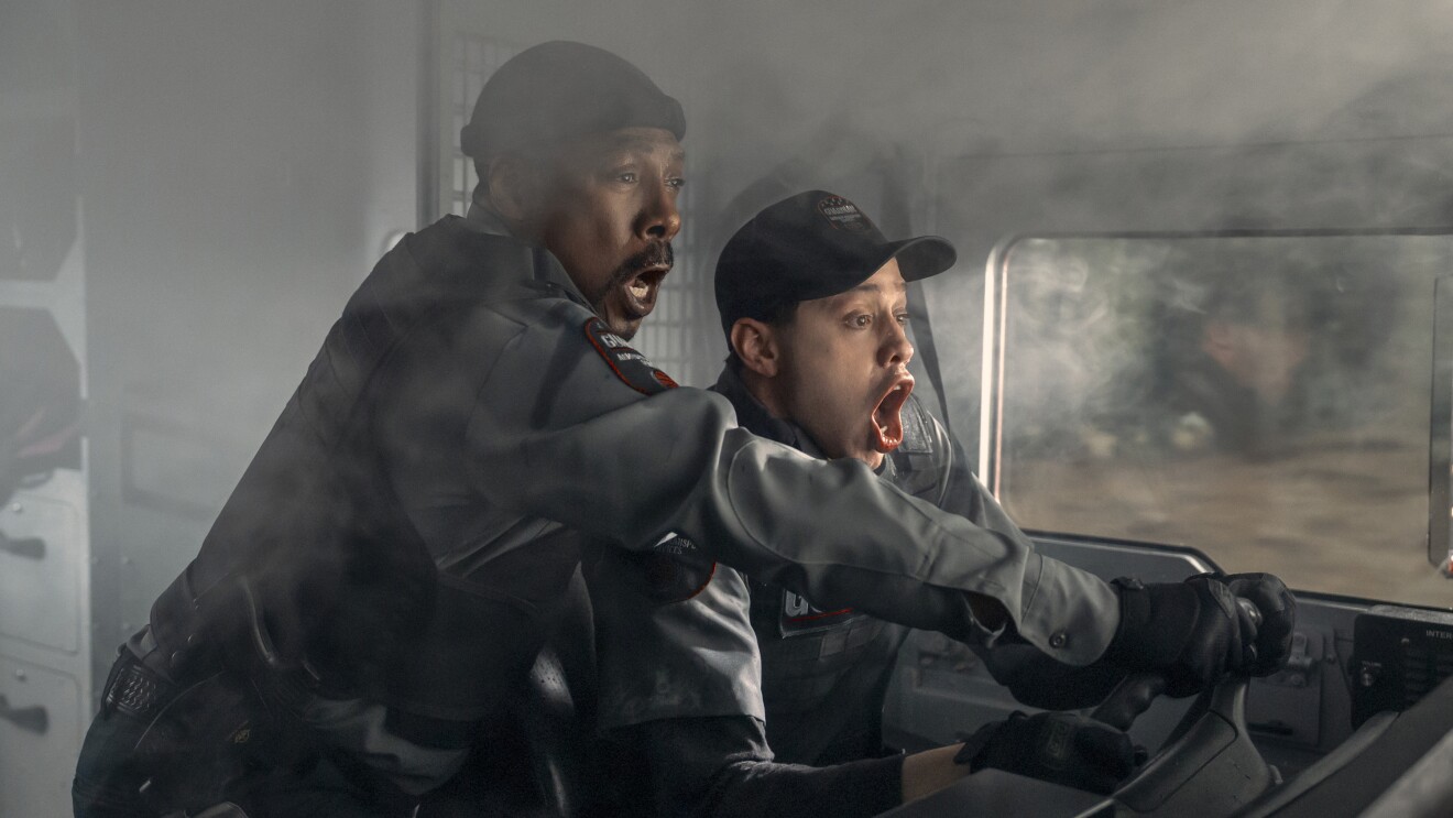 Two men in uniform shouting in alarm while operating a vehicle