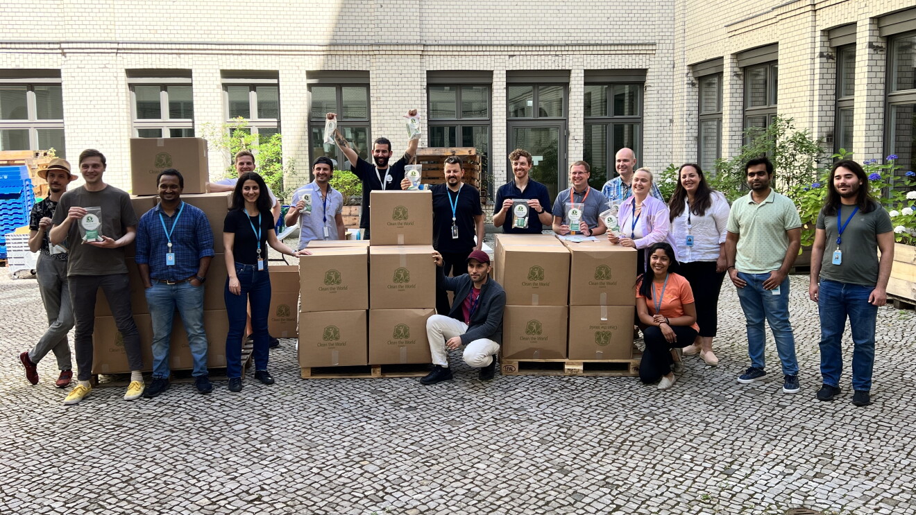 Gruppenfoto von Berliner Mitarbeiter:innen in einem Innenhof mit Kisten, die Hygiene-Kits für Menschen enthalten, die vom Krieg in der Ukraine betroffen sind.