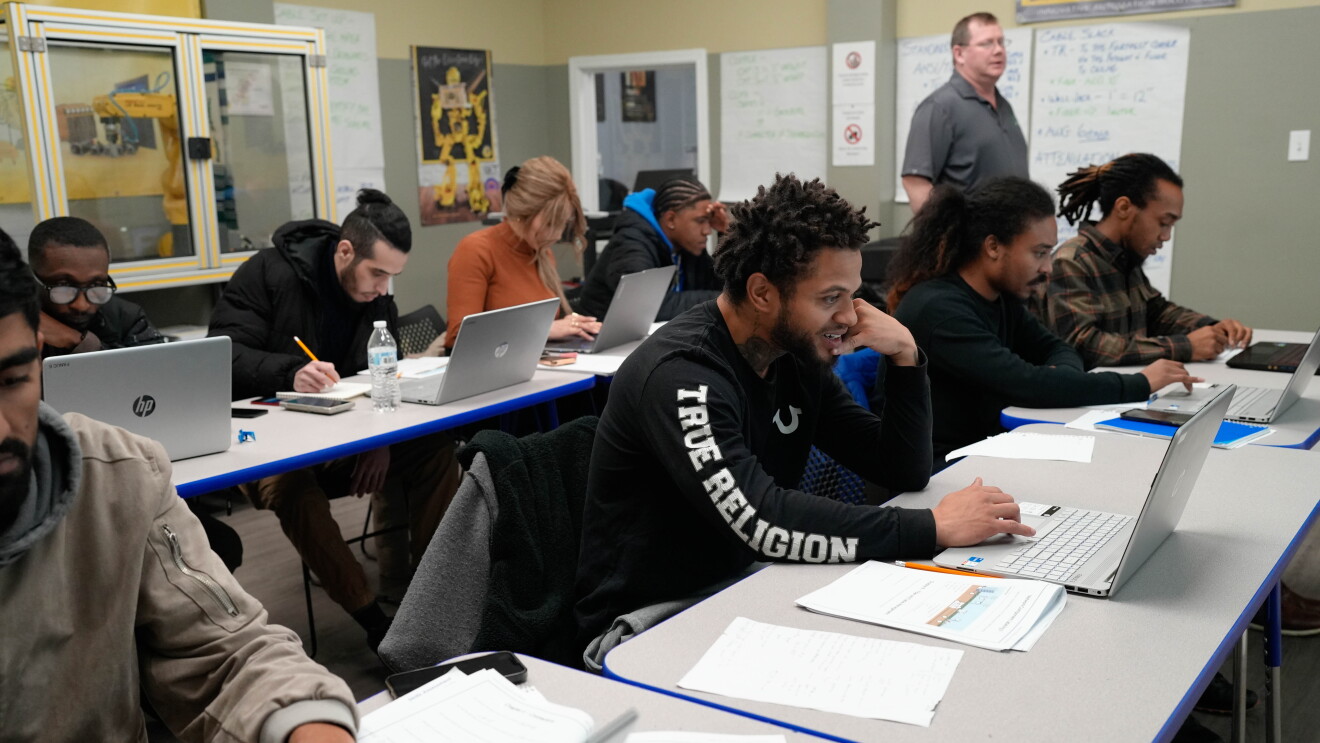Diverse group of students working on laptops in classroom setting